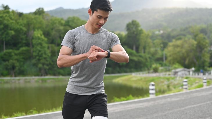 Young Asian athlete man using smartwatch to monitor his activity and progress and track good habits.