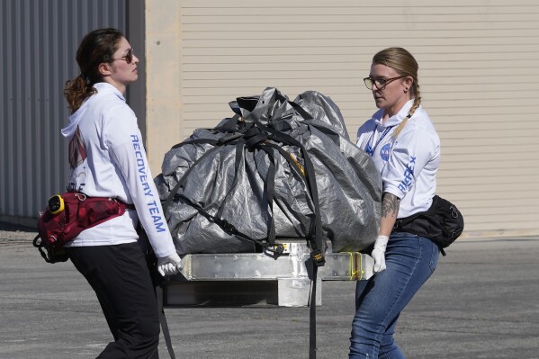 Recovery team members carry a capsule containing NASA's first asteroid samples to a temporary clean room at Dugway Proving Ground in Utah on Sept. 24, 2023. (AP Photo/Rick Bowmer, Pool, file)